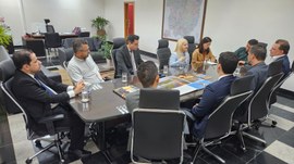A imagem mostra uma reunião institucional no gabinete da Presidência do TRE-MT, com 10 pessoas s...