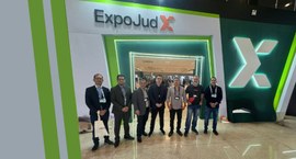 A imagem mostra sete homens em frente à entrada de um evento, identificada pelo letreiro "ExpoJu...