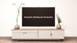 A imagem mostra uma televisão com a mensagem "Horário Eleitoral Gratuito" exibida na tela, posic...