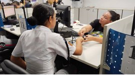 A imagem mostra um atendimento realizado na Casa da Democracia, em Cuiabá. Uma jovem com o unifo...