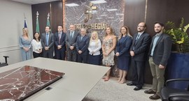 A imagem mostra um grupo de autoridades e servidores do TRE-MT e TRT-MT posando para foto instit...