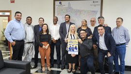 A imagem mostra um grupo de autoridades e representantes institucionais reunidos em ambiente int...