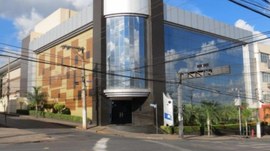 A imagem mostra um edifício comercial moderno localizado em uma esquina urbana. A construção pos...