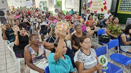 A imagem principal mostra uma atividade com dezenas de pessoas idosas reunidas em um centro de c...