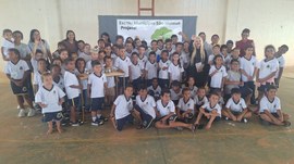 Foto de grupo com dezenas de crianças uniformizadas, junto com a presidente do TRE-MT e educador...