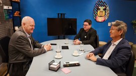 Três homens em trajes sociais, dois do CRC-MT e um do TRE-MT, participam de uma reunião em uma s...