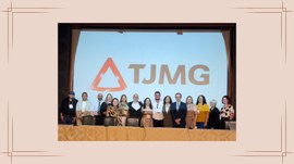 Foto mostra grupo de participantes posando em palco de auditório, em frente a uma tela com a mar...