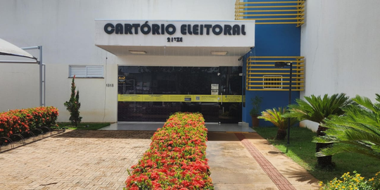 Fachada de um prédio identificado com a placa “Cartório Eleitoral 21ª ZE”, com paredes claras e ...