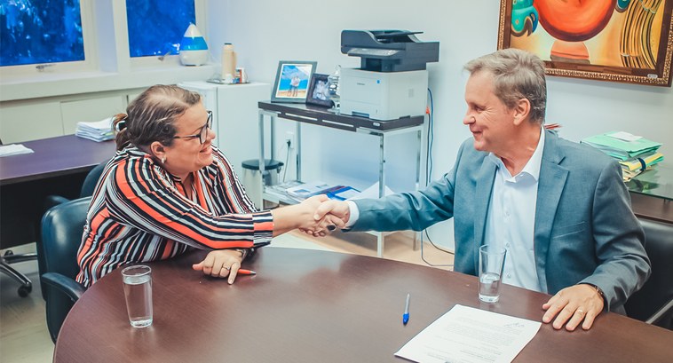 Na foto esta a Secretária de Educação Marioneide estendendo a mão ao Presidente do TRE-MT Desemb...