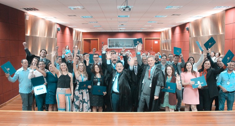 Foto onde mostra todos servidores diplomados diplomados erguendo seus diplomas 