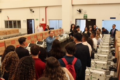 A imagem mostra uma estudante vendo os artefatos dentro do Memorial da Justiça Eleitoral