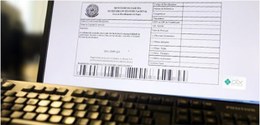 #DescriçãodaImagem: A fotografia mostra uma tela de computador com um boleto e um teclado logo e...