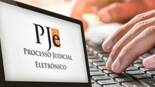 #DescriçãodaImagem: Imagem contendo um computador no qual está escrito em sua tela  PJE - Proces...