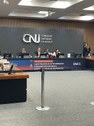 #DescriçãodaImagem: A fotografia mostra a mesa do encontro com as autoridades sentadas e logo at...