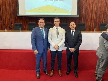 #DescriçãodaImagem: A imagem mostra os três participantes do TRE-MT, são três homens de pé sorri...